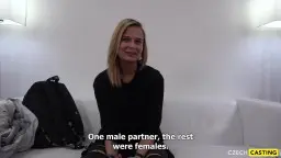 Blonde mit Zöpfen lächelt verführerisch auf weißer Couch sitzend