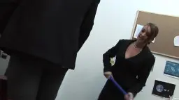 Reife Lehrerin in schwarzem Blazer mit Stock vor Tafel