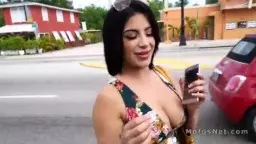 Latina in geblümtem Kleid hält Geld und Handy auf Straße