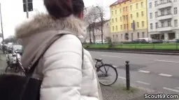 Frau in weißer Winterjacke steht vor Haus