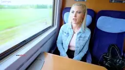 Blonde Frau allein am Zugfenster mit grüner Landschaft
