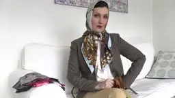 Frau in braunem Blazer und Kopftuch auf weißem Sofa