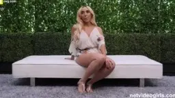 Blonde Milf mit großen Brüsten sitzt auf weißer Outdoor-Couch