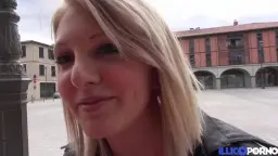 Blonde mit Lederjacke auf Parkbank, Lächeln in die Kamera.
