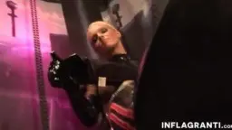 Domina in schwarzem Latex vor violetter Beleuchtung