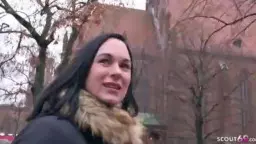Reife Frau in Winterjacke lächelt vor Backsteinkirche