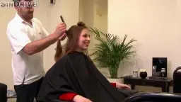 Kundin unter schwarzem Umhang, Friseur mit Schere im Salon