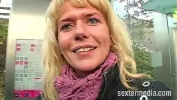 Blonde Frau im lila Schal lächelt in Kamera.