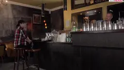Frau sitzt auf Barhocker, kariertes Hemd, Bar im Hintergrund